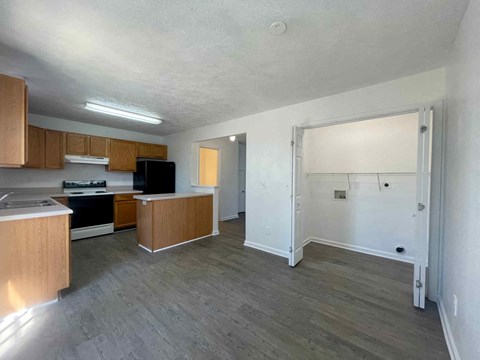 A kitchen with wooden cabinets and a black fridge is visible.