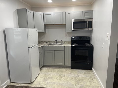 A kitchen with a white refrigerator, a black oven, and a microwave above the stove.