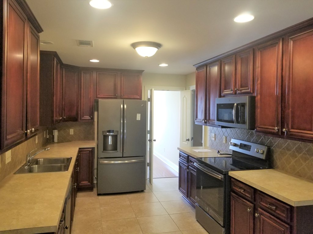 A kitchen with brown cabinets and a black stove top oven.