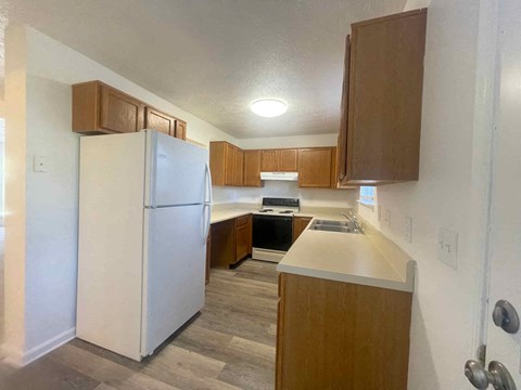a kitchen with wooden cabinets and a refrigerator and a sink