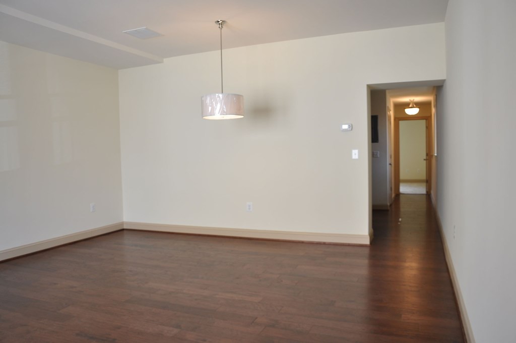 an empty living room with wood floors and a white wall