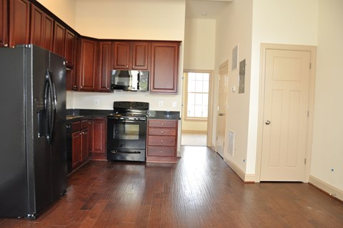 an empty kitchen with black appliances and wooden floors