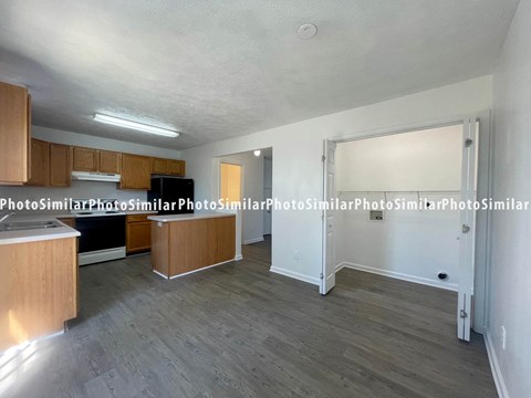 A kitchen with wooden cabinets and a black fridge.