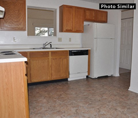 A kitchen with wooden cabinets and a white refrigerator.