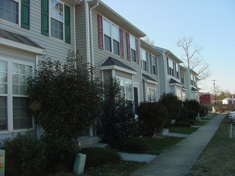 A long row of houses with green bushes in front.