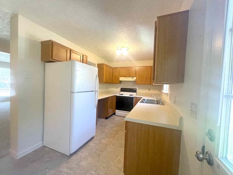 A kitchen with a white refrigerator and wooden cabinets.
