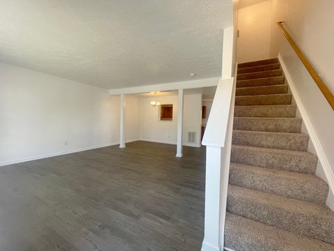 the upstairs living room and dining room with carpeted stairs and white walls