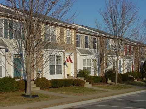 A row of apartment buildings with trees in front.