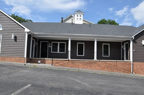 A building with a grey roof and a brick wall with a black iron fence in front.