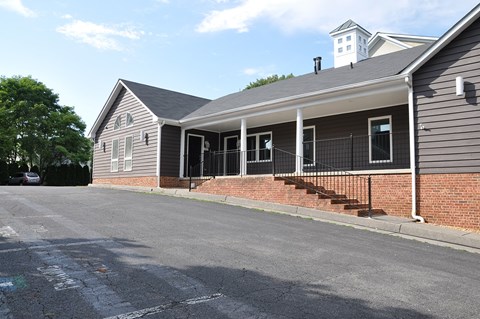 A grey house with a black iron fence and a brick wall.