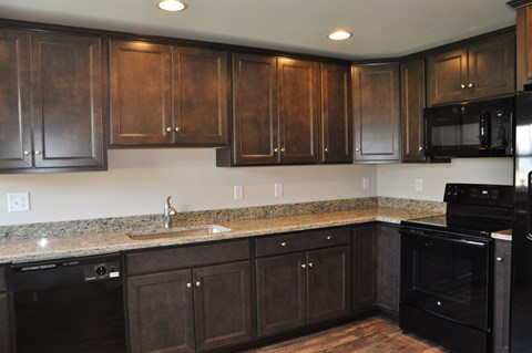 A kitchen with dark wood cabinets and black appliances.