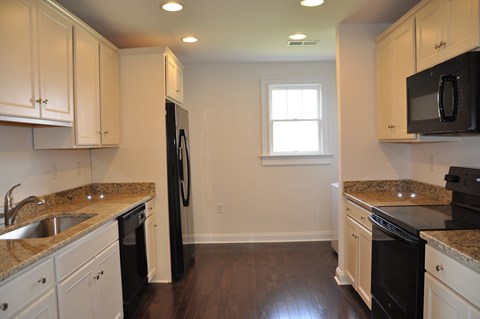 A kitchen with black appliances and white cabinets.