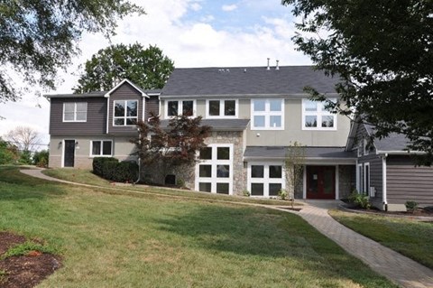 A grey house with a red door and white windows.