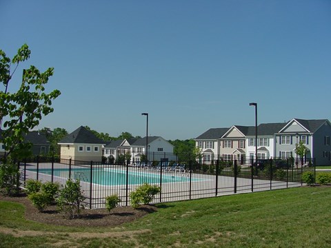 A pool surrounded by a black fence and a few trees.