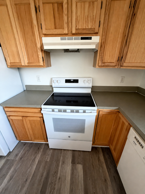 A kitchen with wooden cabinets and a white stove top oven.