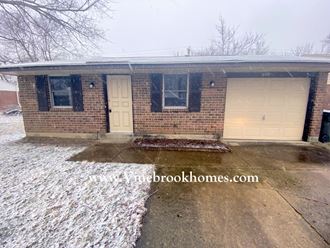 a small brick house with two garage doors in the snow