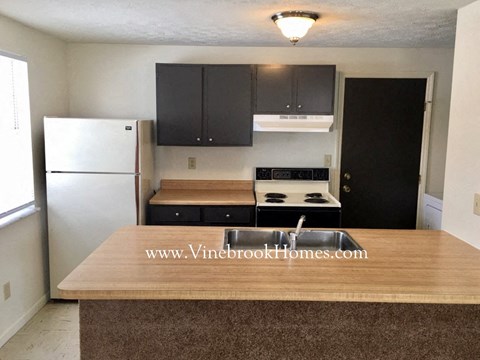a kitchen with black cabinets and a white refrigerator