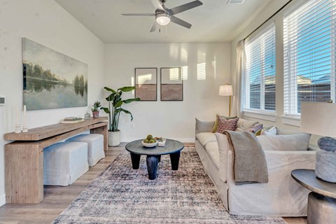 A living room with a white couch, a coffee table, and a painting on the wall.
