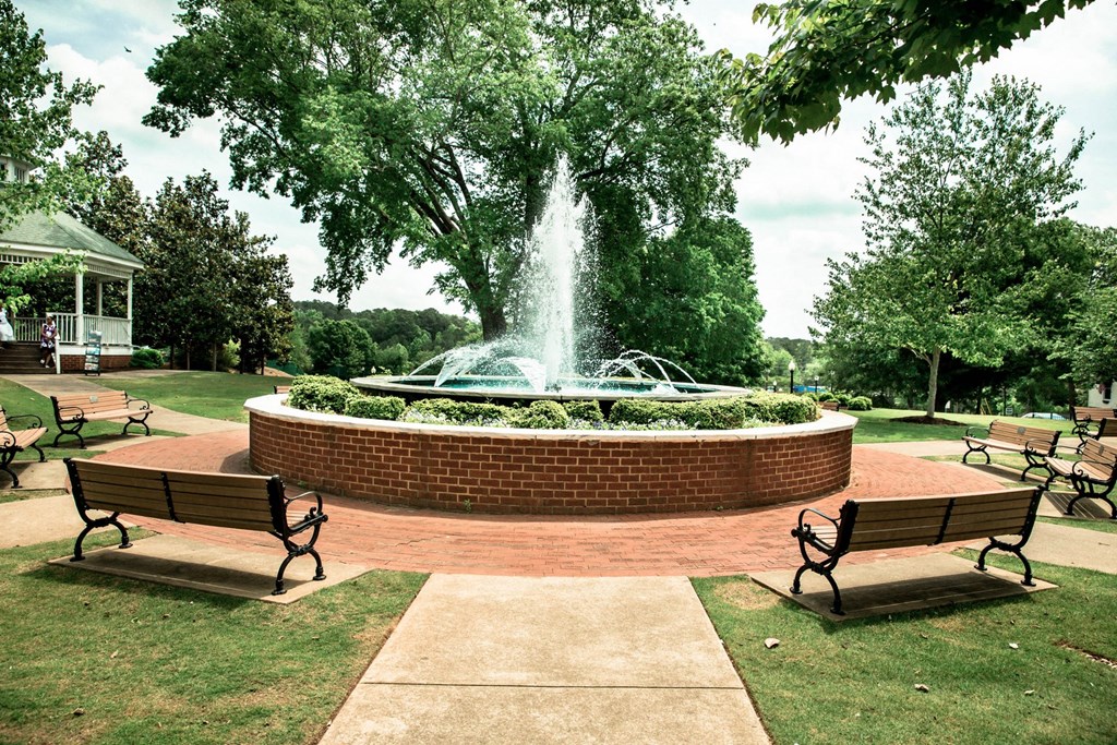 a fountain in the middle of a park with benches