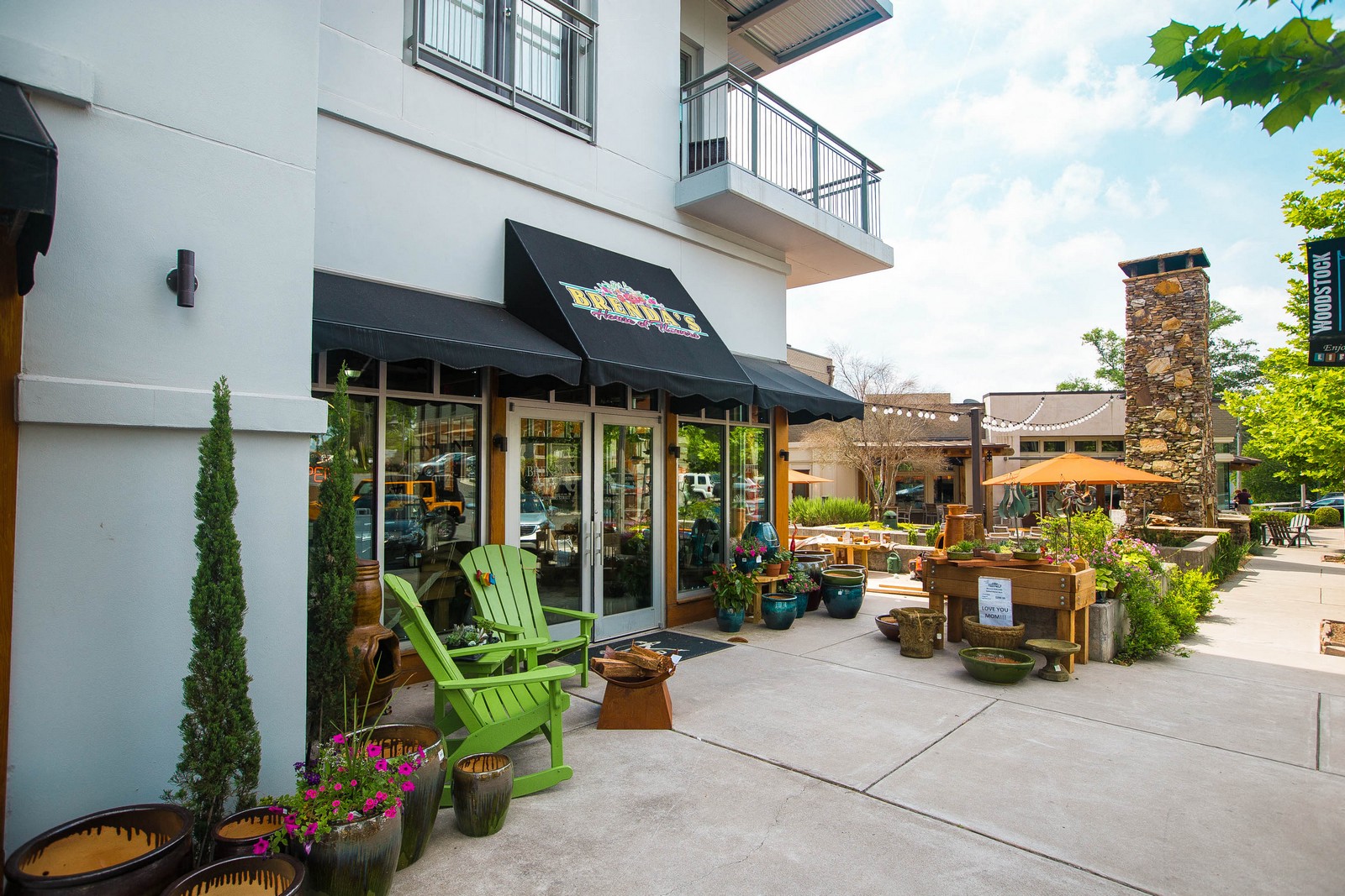 a patio outside of a building with green chairs and potted plants
