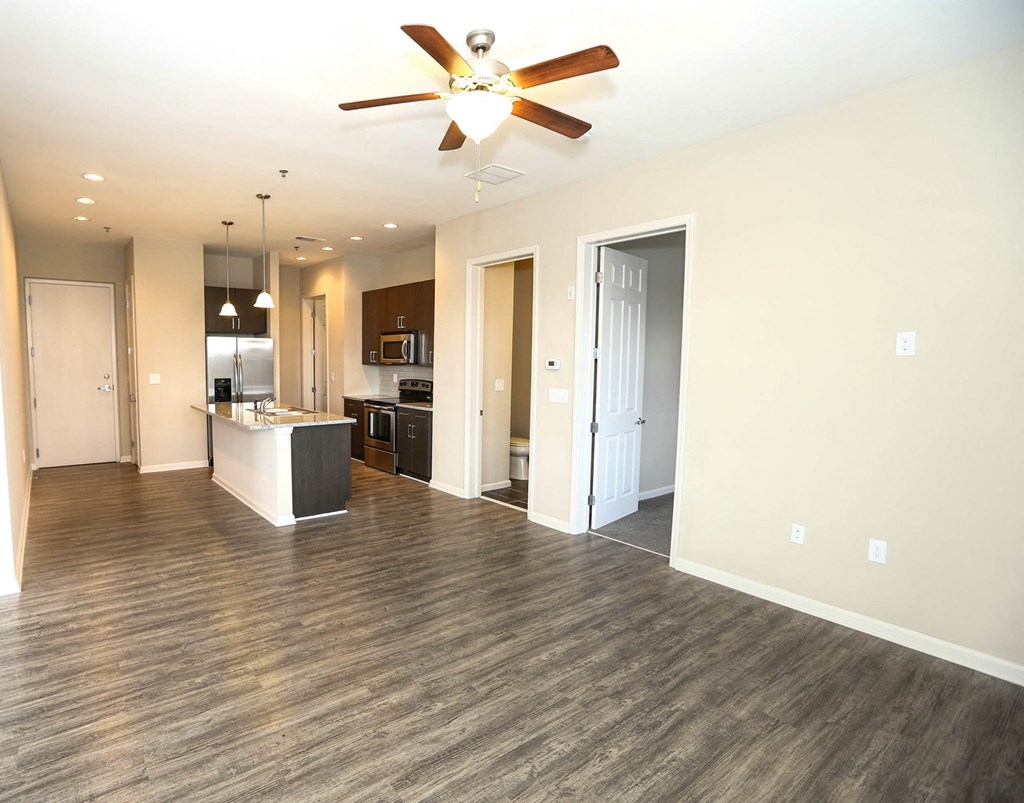 an empty living room with a ceiling fan and a kitchen