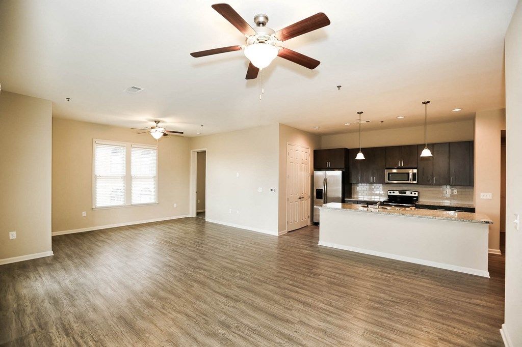 an empty living room and kitchen with a ceiling fan
