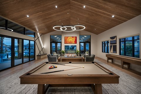 a pool table in the center of a large room with windows