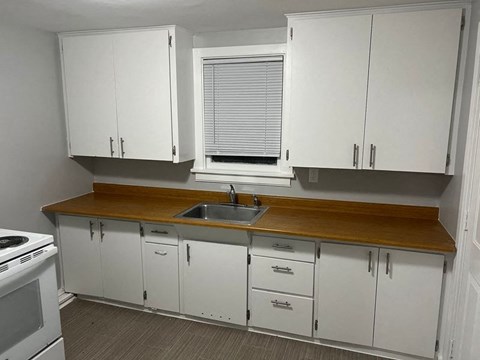 A kitchen with white cabinets and a wooden countertop.