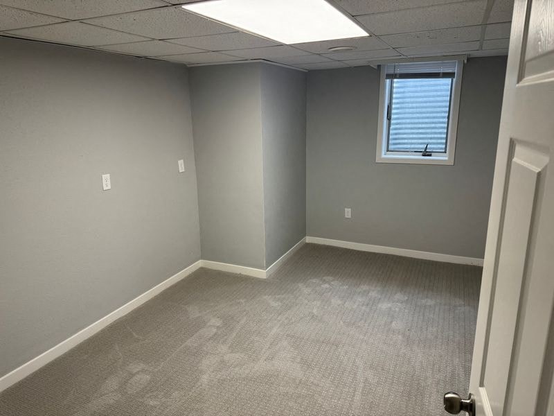 A room with a carpeted floor and a door on the right side.