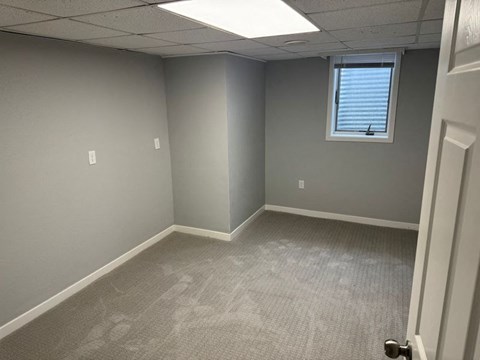A room with a carpeted floor and a door on the right side.