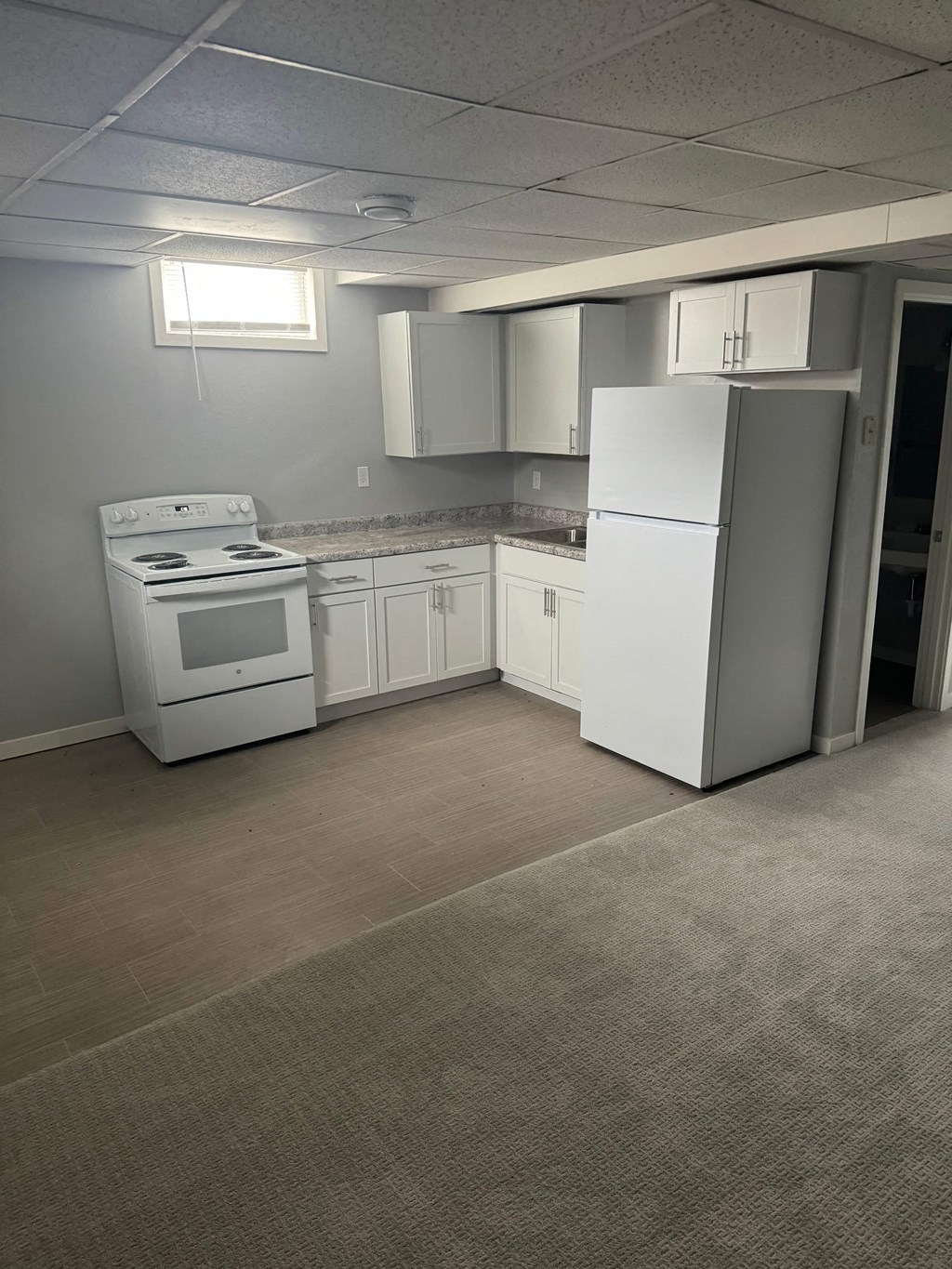 A white refrigerator is in a kitchen with white appliances.