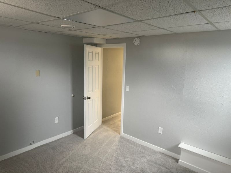 A room with a carpeted floor and a white door.