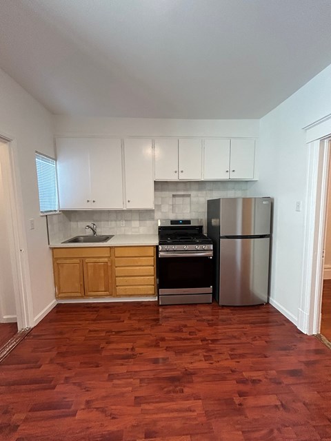 A kitchen with wooden cabinets and a stainless steel refrigerator.