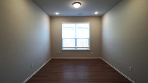 a empty room with a window and wooden floors
