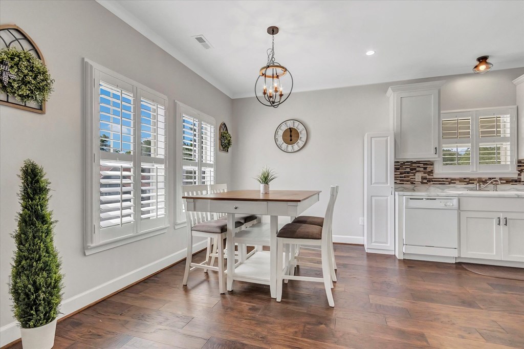 a dining room with a table and chairs and a kitchen with white cabinets