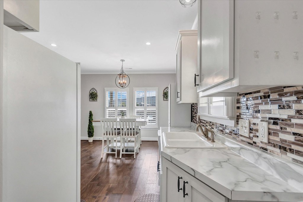 a kitchen with white cabinets and a dining room with a white table and chairs