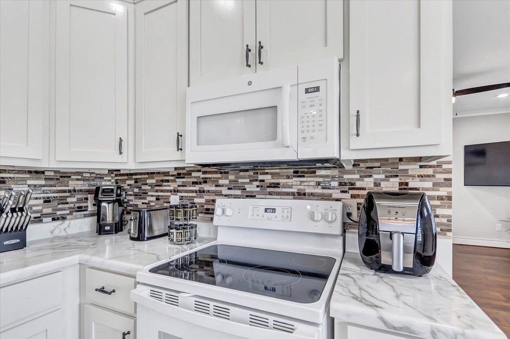 a kitchen with white cabinets and a stove and microwave