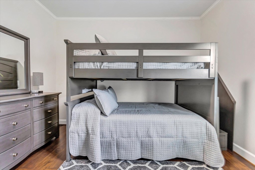 a bunk bed in a bedroom with a dresser and a tv