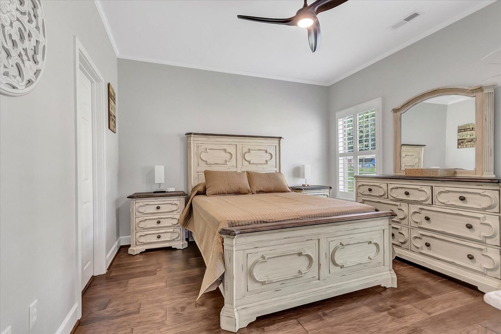 a bedroom with a bed and dressers and a ceiling fan
