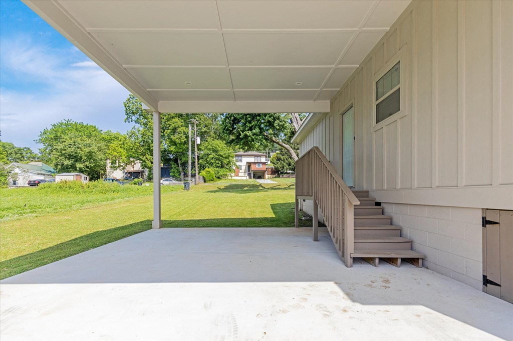 the front porch of a home with stairs and a yard