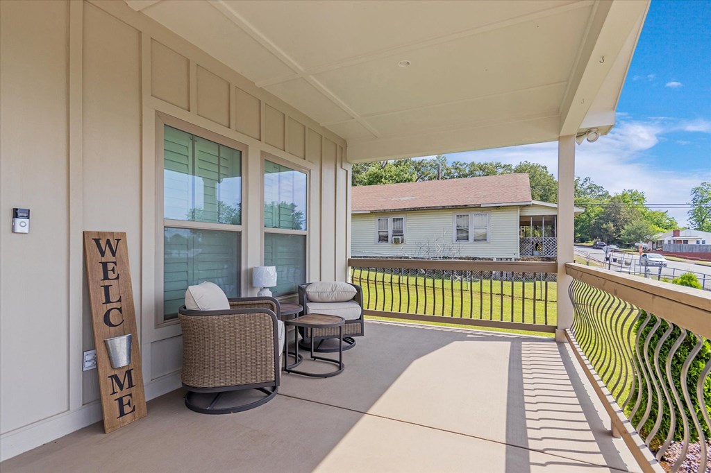a covered porch with two chairs and a table