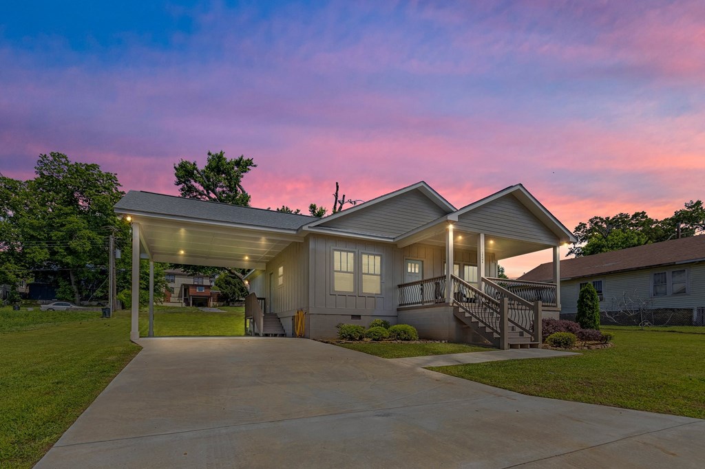 a home with a driveway and a covered porch at sunset