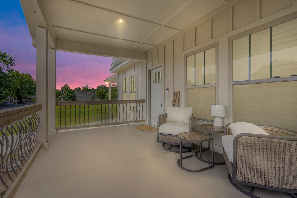 a covered porch with two chairs and a table