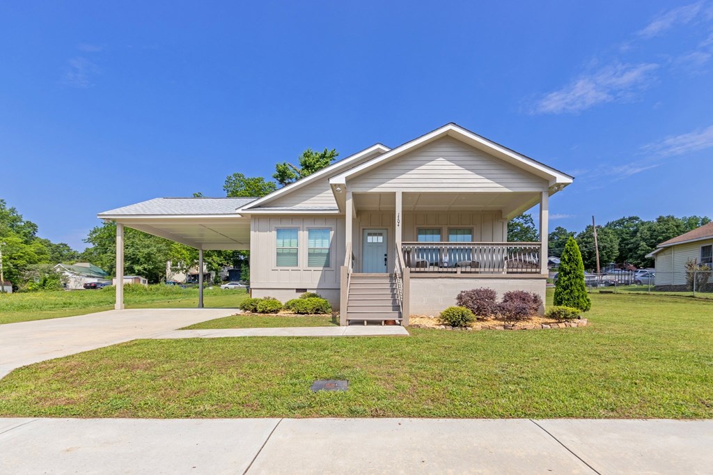 a small white house with a porch and a lawn