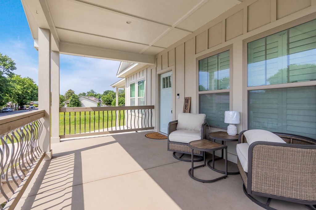 the front porch of a house with two chairs and a table