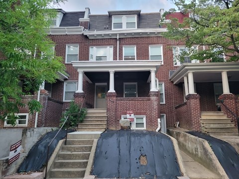 the front of a brick house with a black tarp on the stairs