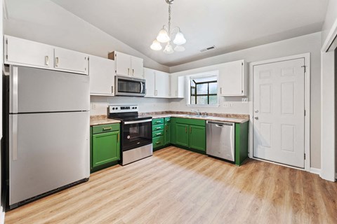 a kitchen with green and white cabinets and appliances