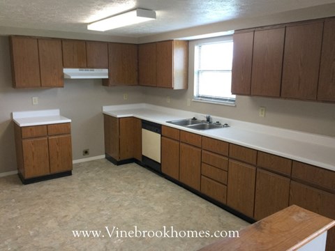 A kitchen with wooden cabinets and a white counter top.