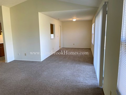 the living room of an apartment with carpet and white walls