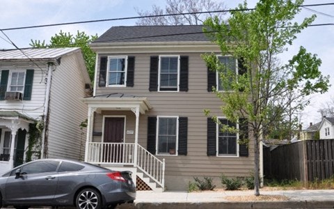 A grey house with a car parked in front.
